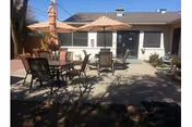 Outdoor patio area with tables, chairs, and umbrellas in front of a single-story nursing home building.