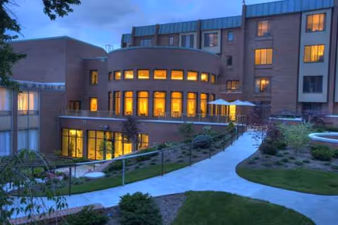 Evening exterior view of Marjorie P. Lee retirement community with curved glass facade.