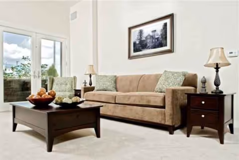 Cozy living room with beige sofa, coffee table, lamps, and framed wall art.