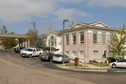 Exterior view of Life Care Center of Colorado Springs with parked cars and accessible entrance.