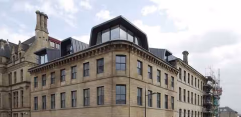 A large stone building with many windows and rooftop extensions.