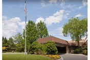 Exterior view of Stonegates with flagpole, trees, and front driveway.