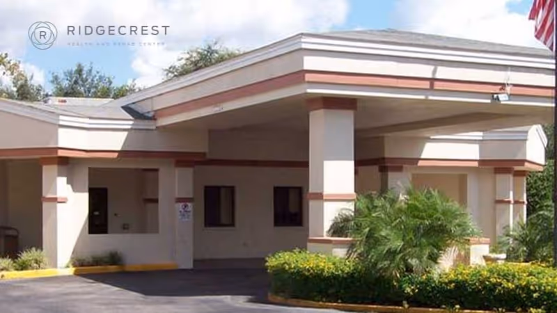 Covered front entrance/porte-cochère of a single-story health and rehab center with driveway and landscaping.