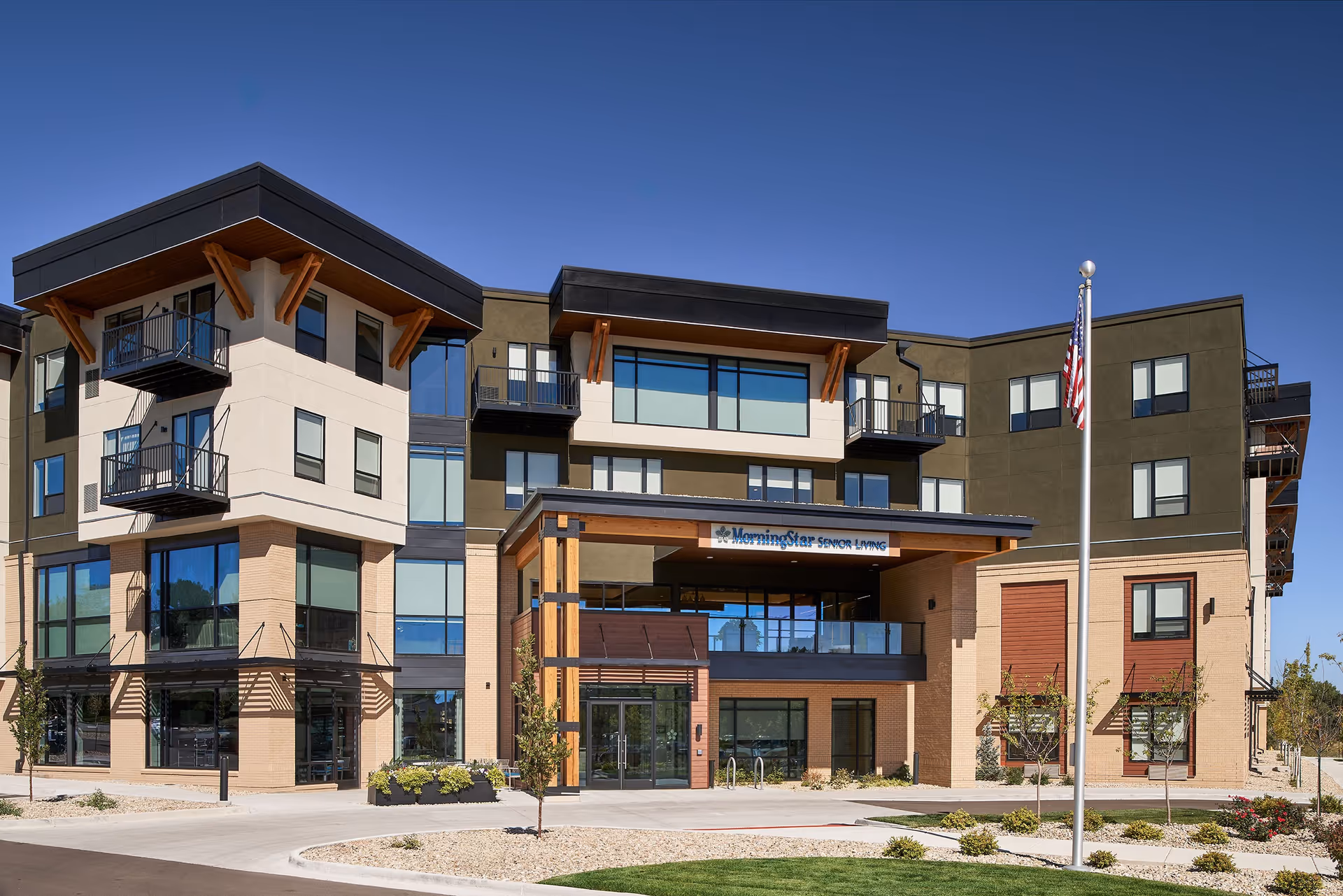 Modern multi-story MorningStar Senior Living building exterior with balconies, a covered main entrance, and an American flag.