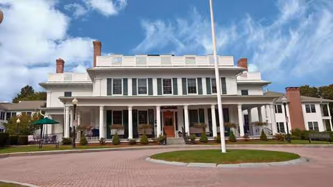 Atria Harborhill's white, columned senior living facility facade with a circular brick driveway.