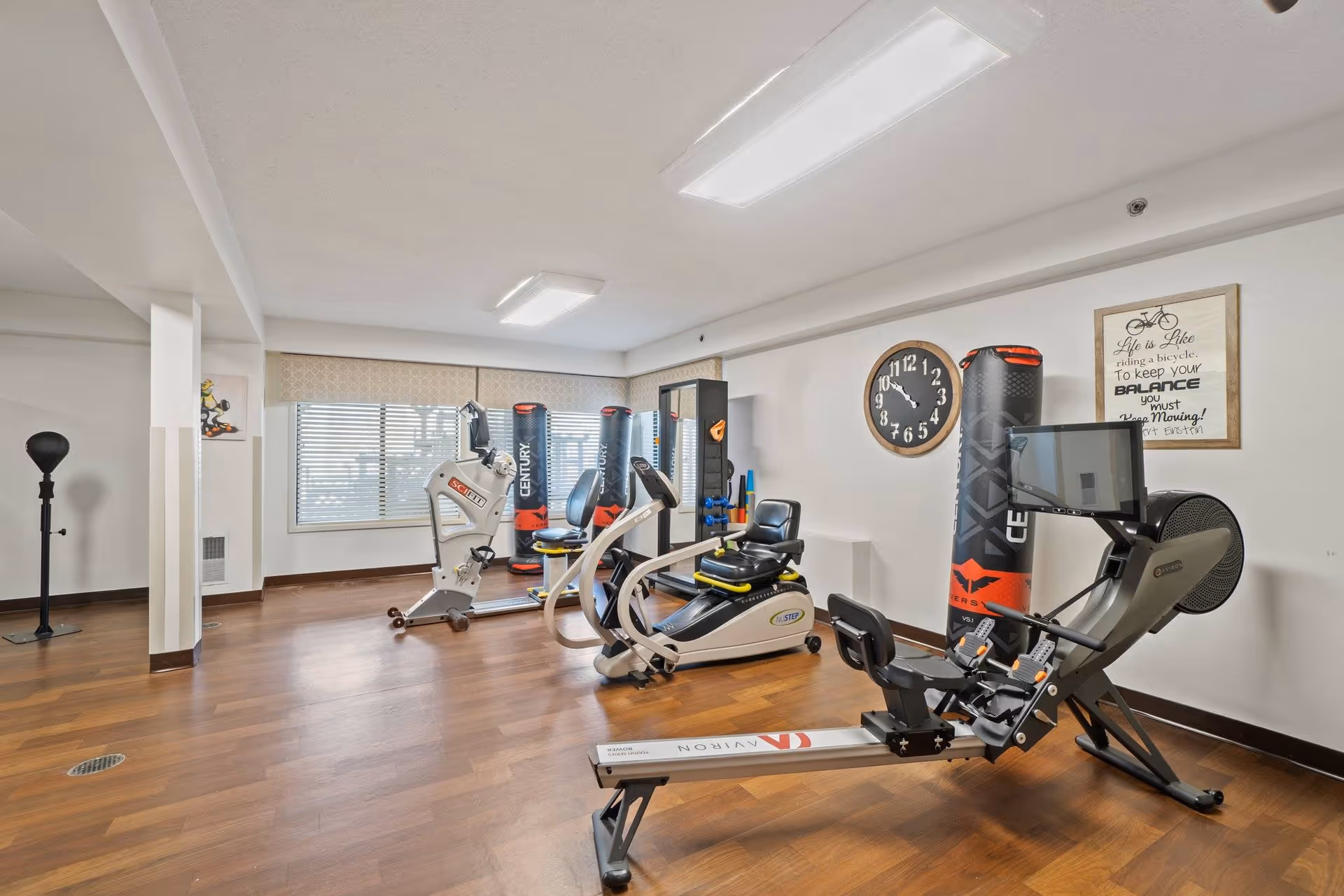 Interior fitness room with treadmills, stationary bikes, and punching bags.