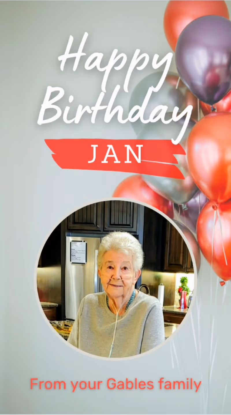 Birthday greeting card with balloons and a photo of an elderly woman in a kitchen. Text reads 'Happy Birthday JAN' and 'From your Gables family'.