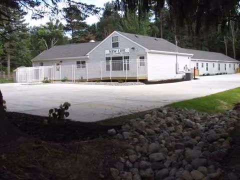 Front view of a single-story white assisted living center with surrounding trees