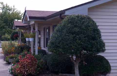 The front exterior of Traceway Retirement Community features manicured shrubs and a walkway.