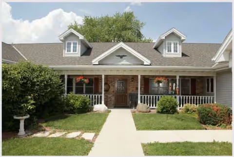 Front view of a single-story assisted living facility with a central doorway and porch.