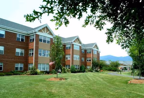 Exterior view of Tryon Estates senior living facility with brick facade and lawn.