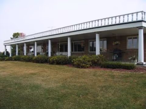 Long, single-story brick facility with a covered veranda and well-kept lawn.