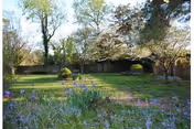 Lush outdoor lawn with flowering plants and trees in front of Lydia H. Roper Home.