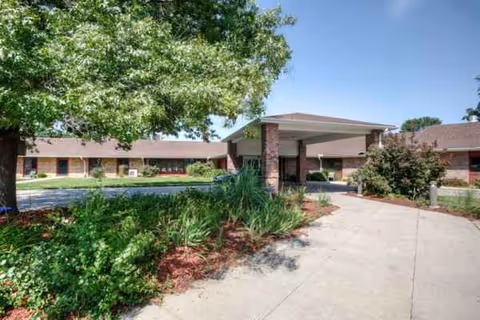 Front view of a single-story senior living facility with a covered entrance and landscaping.