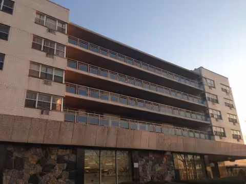 Front view of Bridge View Nursing Home, a multi-story building with balconies and a stone base.