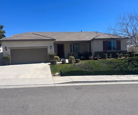 Single-story suburban house with an attached two-car garage, front lawn, driveway and clear blue sky.