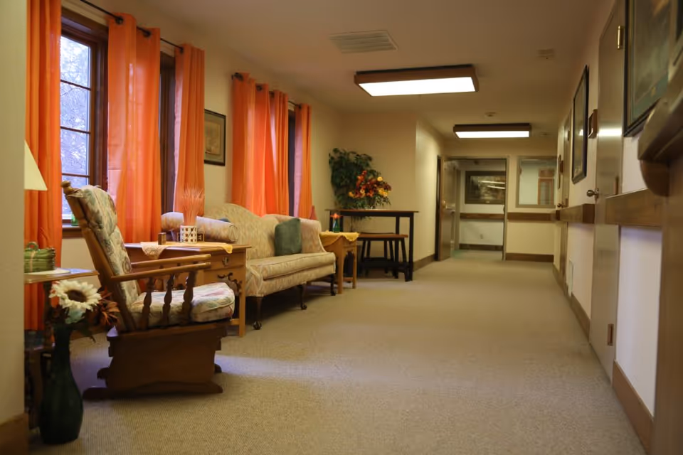 Cozy hallway seating area with upholstered armchairs, a sofa, side tables and orange curtains.