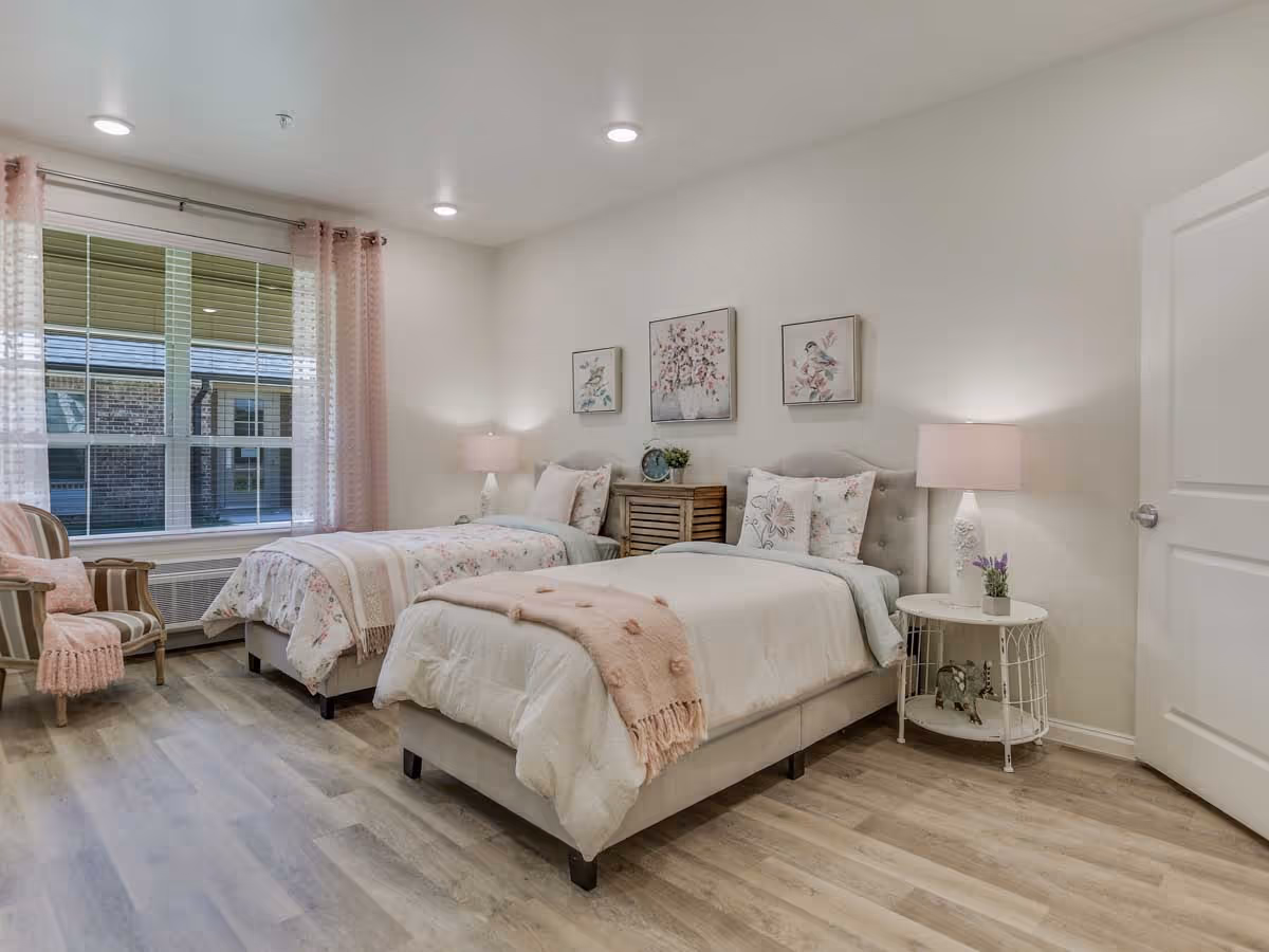 Bright, well-decorated bedroom with two twin beds, pastel bedding, bedside tables and a large window.