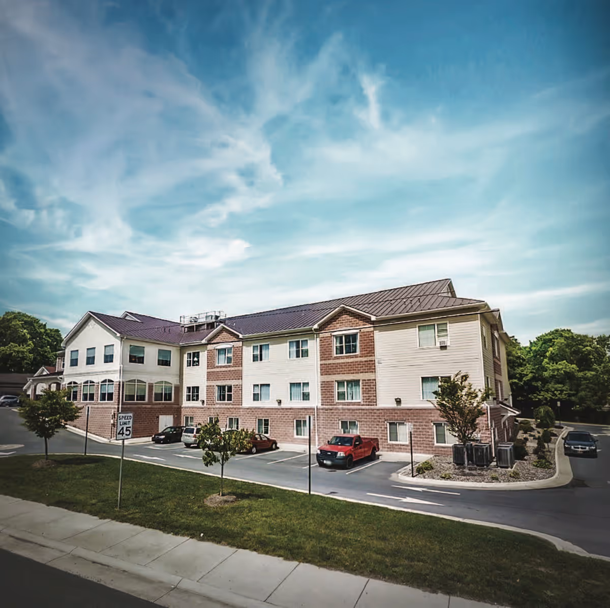 Exterior view of Hilltop senior living building with parking lot and landscaping.
