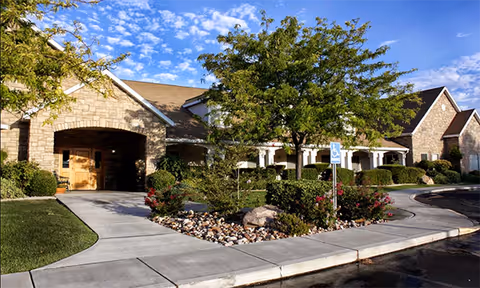 Ridgeview Gardens Assisted Living exterior with stone facade, trees, and landscaped entrance.