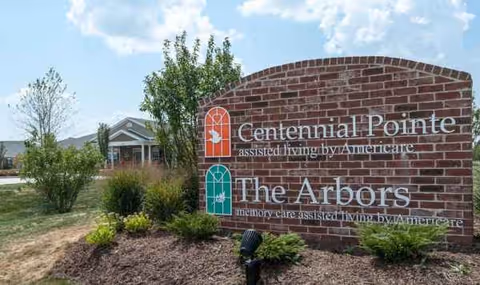 A brick sign for The Arbors at Centennial Pointe in front of a building.