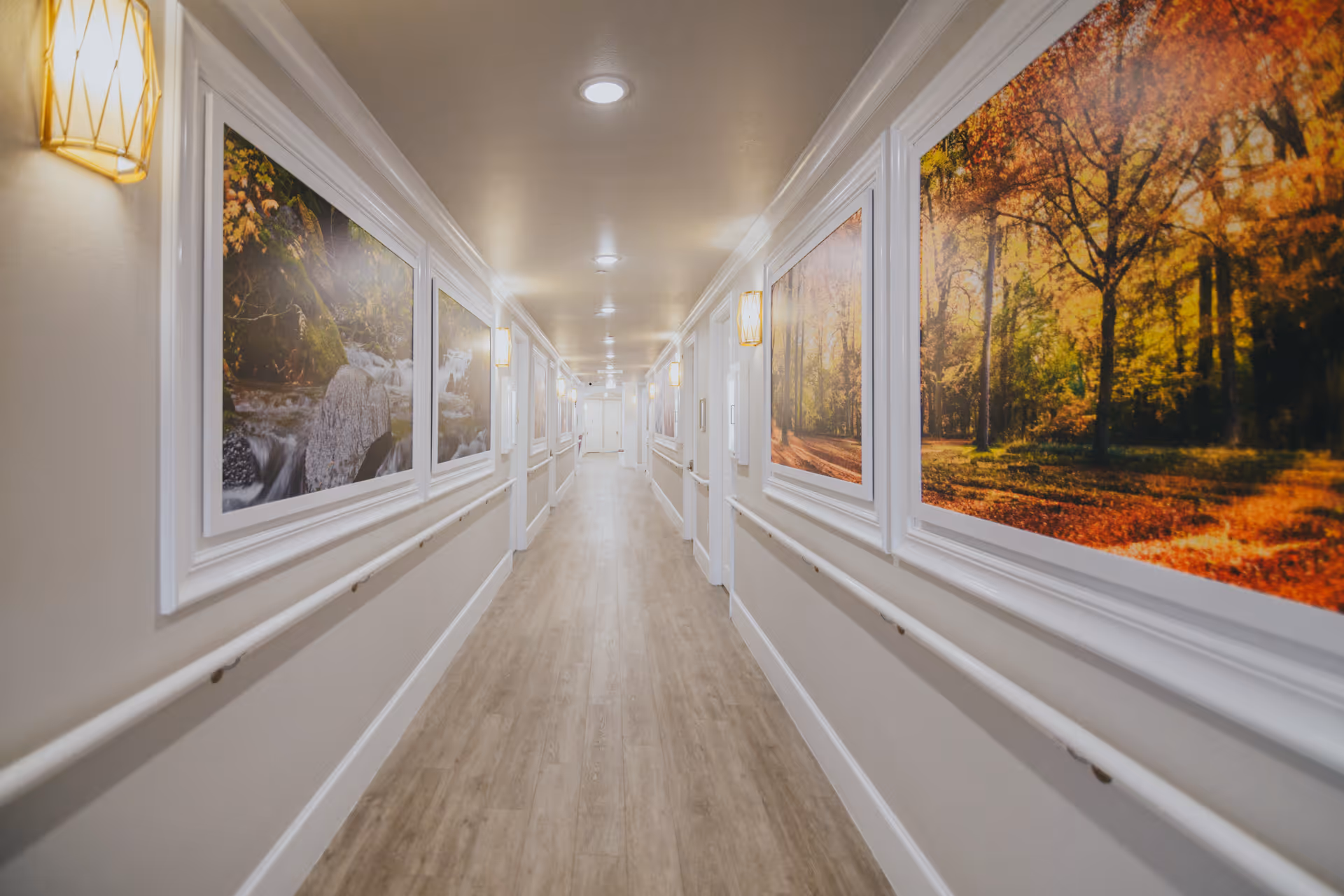 Long, well-lit interior hallway with handrails and large framed nature artwork along the walls.