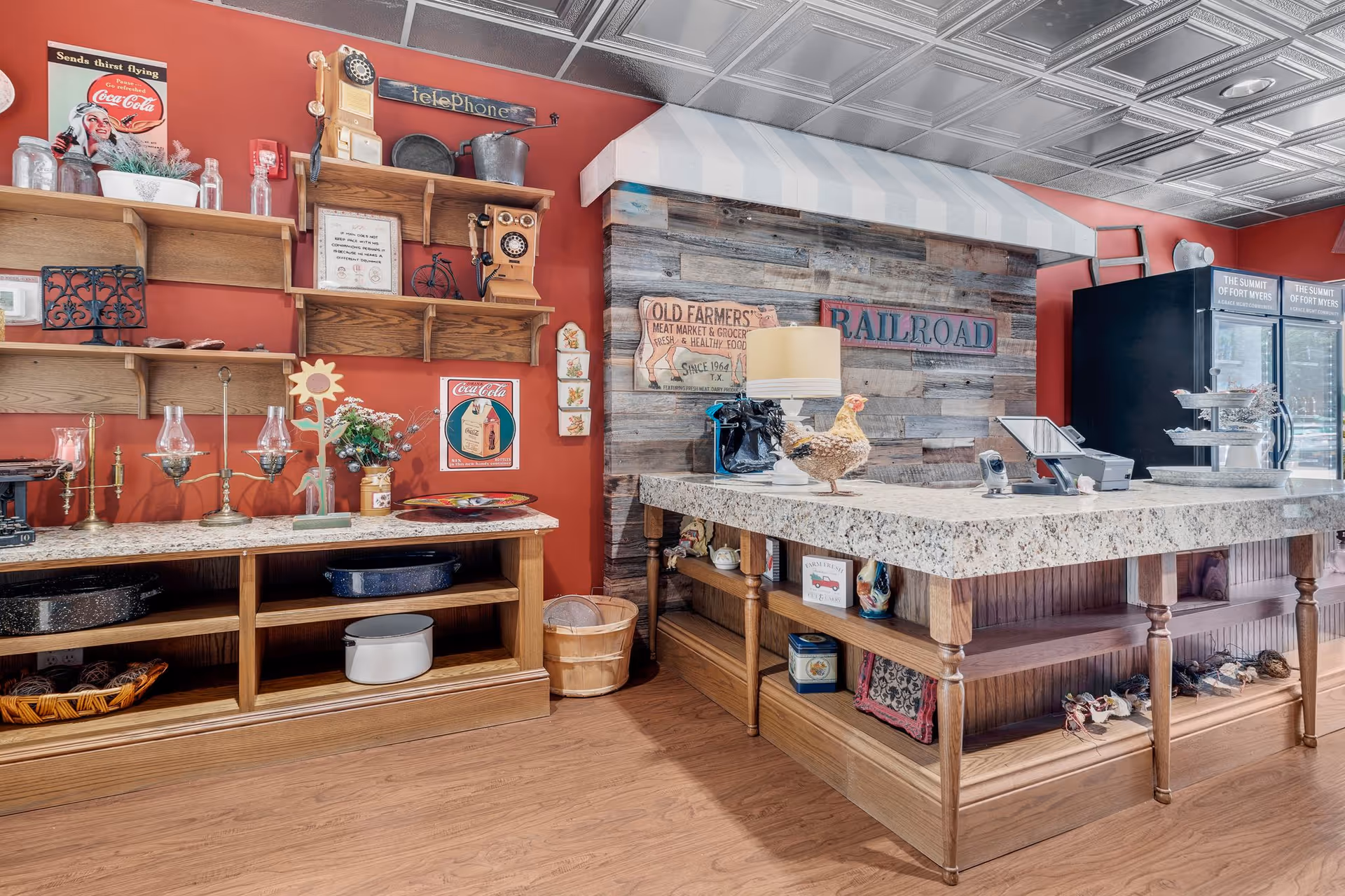 Country-style indoor food-service counter with wooden shelves, vintage signs, and a display refrigerator.