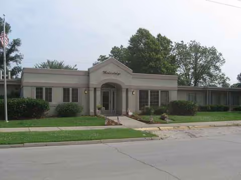 Exterior view of a single-story beige senior living facility with entrance.