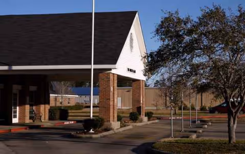 Front entrance of Village Creek Rehabilitation and Nursing Center with brick columns and a parking lot