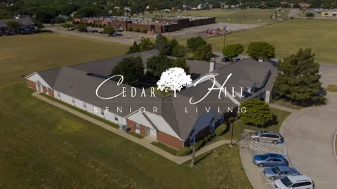 Aerial view of the Cedar Hill Senior Living building with lawns, trees, and a small parking lot.