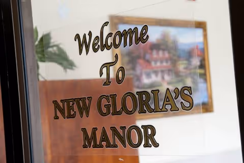 Glass door with 'Welcome to New Gloria's Manor' sign visible at entrance.