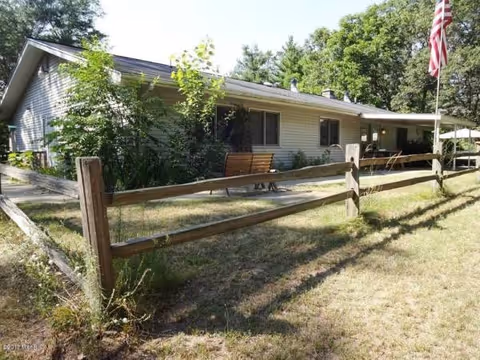 A single-story senior living facility sits behind a wooden fence with benches and an American flag.