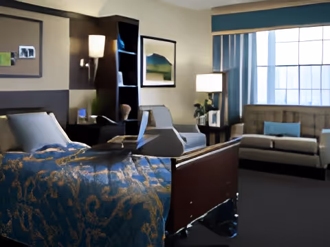 Resident bedroom with a bed, seating area including chairs and a sofa, lamps, and a large window.