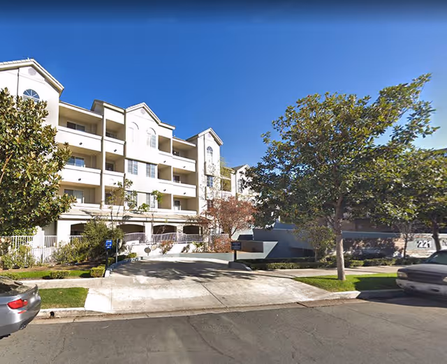 Glen Terra Assisted Living exterior: three-story building with balconies, driveway, and trees along the entrance.