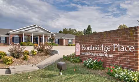 Front entrance of NorthRidge Place assisted living with a brick sign and landscaping.