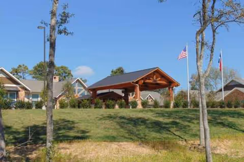 Wood Glen Court senior living facility entrance with a wooden porte-cochère and flags.