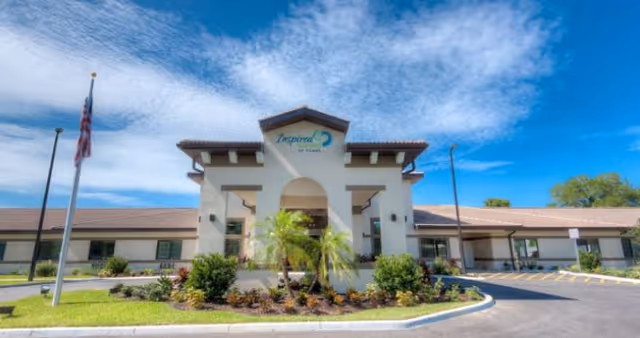 Front exterior view of Inspired Living Tampa facility with entrance arch and landscaping.
