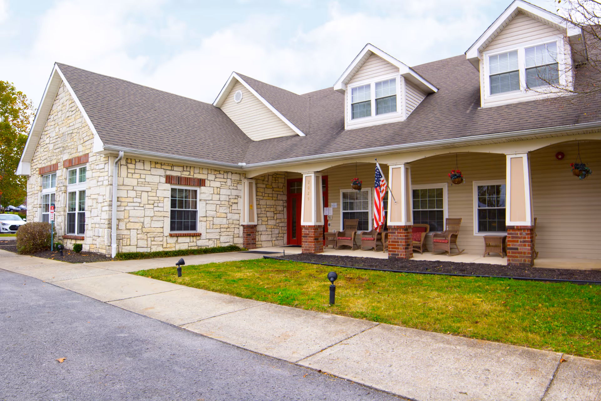 Exterior view of Brookdale Goodlettsville building with stone facade, porch seating, and American flag.