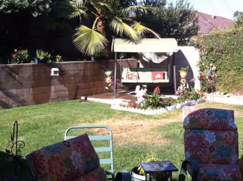 Outdoor backyard patio with a swing bench, colorful chairs, and garden at Ivy Cottage.