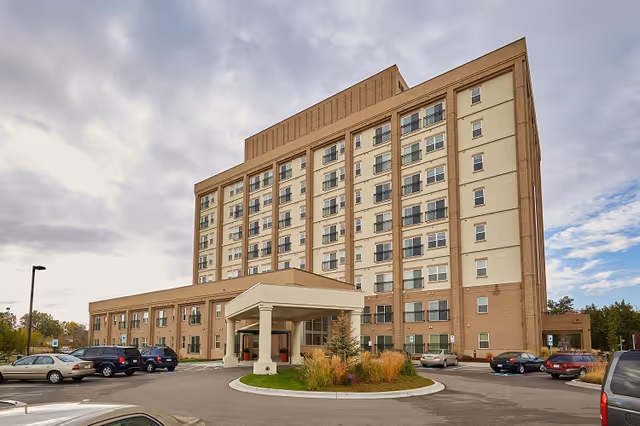 Bella Vita senior living building with a covered entry, multi story facade, and surrounding parked cars.