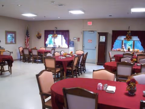Dining hall in a senior living facility with red tablecloths and chairs.