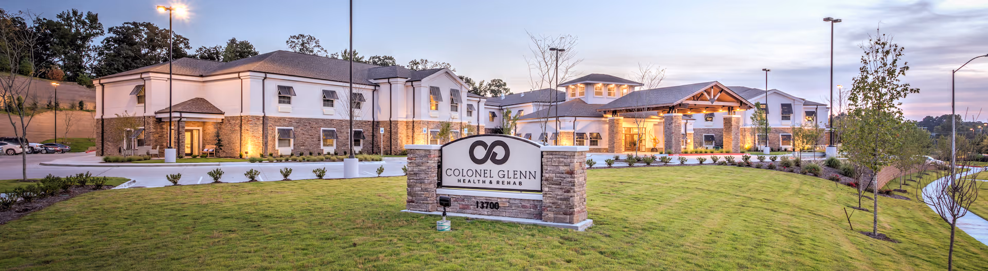 Exterior view of Colonel Glenn Nursing and Rehab facility with a landscaped lawn.
