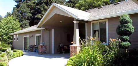 A single-story senior living facility exterior with a covered entrance and landscaped front yard.