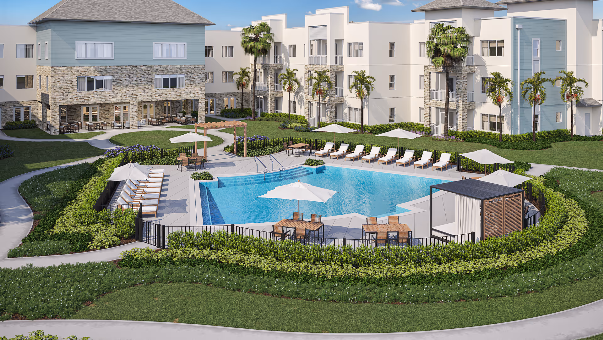 Outdoor view of AVIVA Port St. Lucie West senior living facility featuring a large swimming pool surrounded by lounge chairs and umbrellas. The pool area is enclosed by a black fence and landscaped with green bushes. There are tables with umbrellas and chairs around the pool, as well as a shaded cabana. The background shows multi-story buildings with stone and light-colored exterior walls, palm trees, and a clear blue sky.