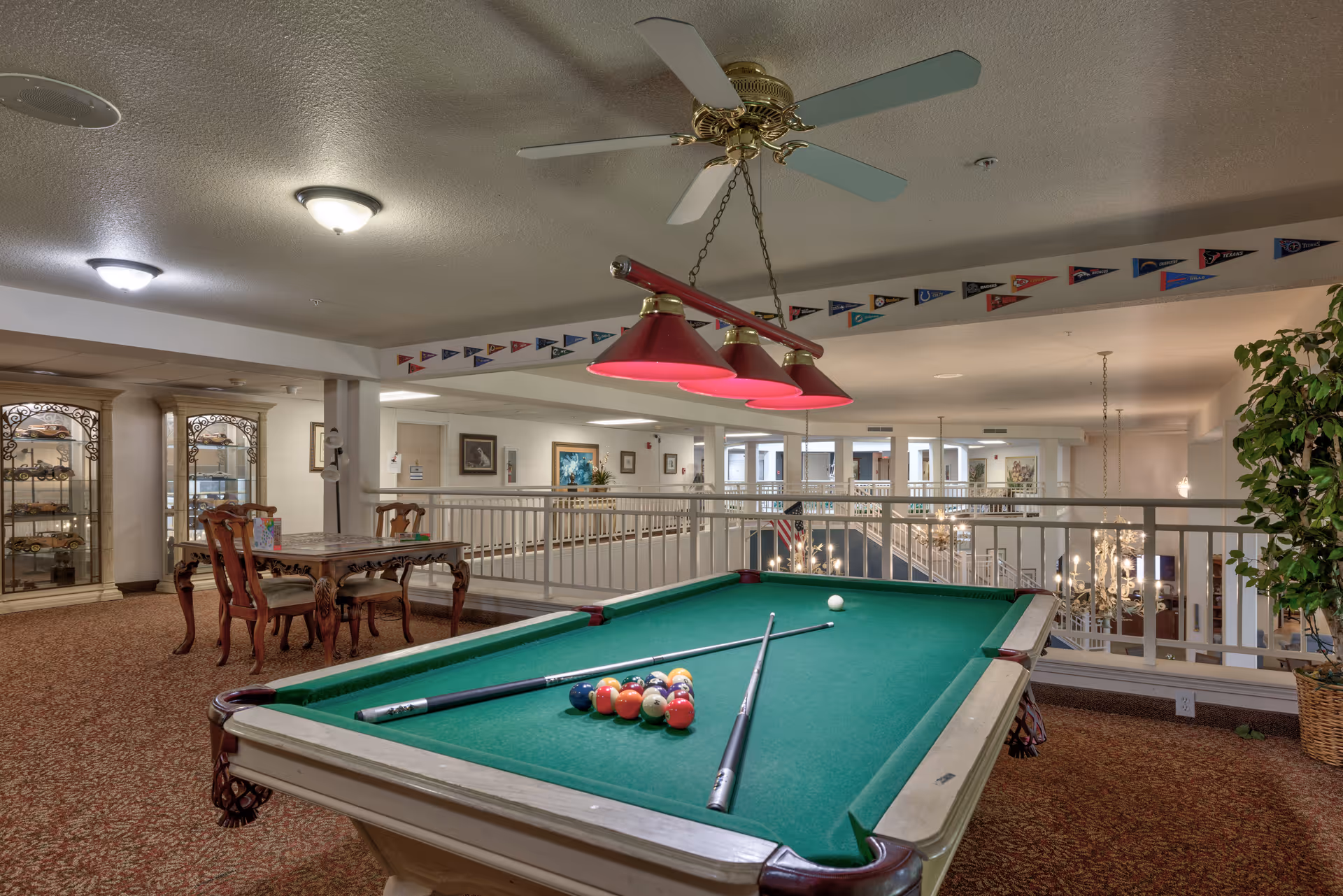 Interior common area with a pool table, overhead lights, seating, and railing overlooking a lower level.
