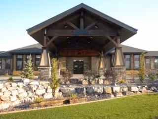 Exterior entrance of Stonehenge of Richfield with stone landscaping and wooden covered entryway.