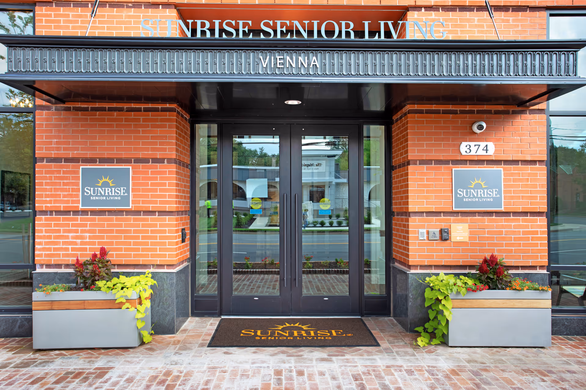 Brick building exterior with glass doors and Sunrise Senior Living Vienna signage.