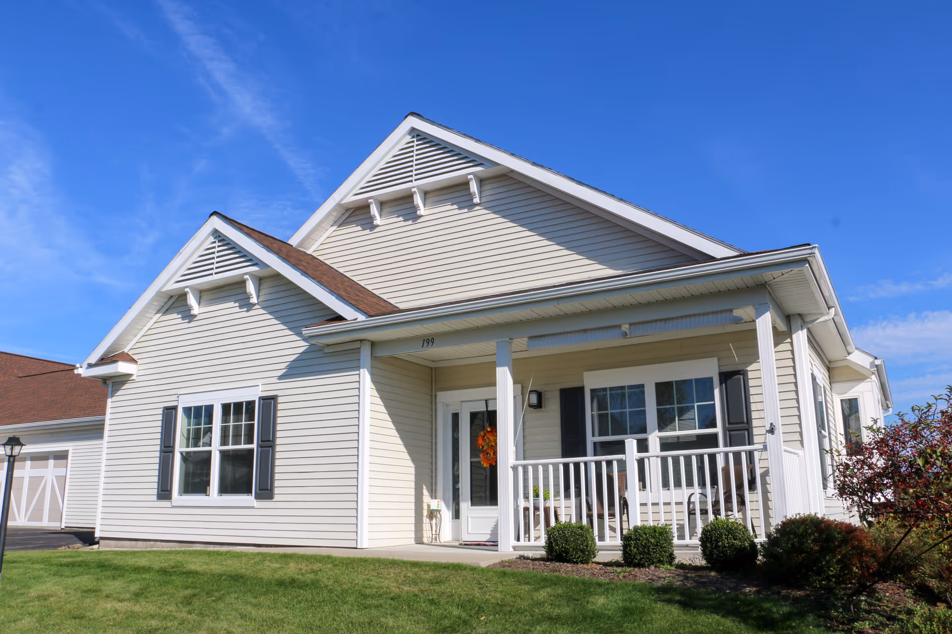 Exterior of a single-story beige senior living facility with porch and lawn.