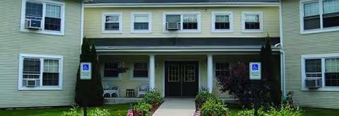 Front exterior view of Holy Cross Senior Housing entrance with columns and signage.