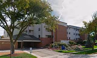 Exterior view of Stone Terrace Retirement Living Center with trees and landscaping.
